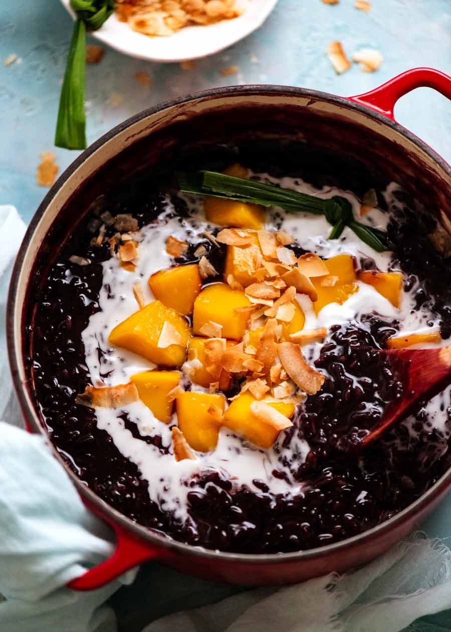 Thai Black Sticky Rice Pudding in pot with mango and coconut