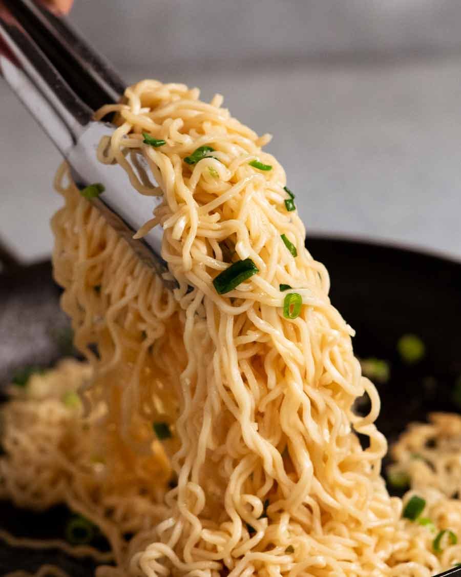 Tongs picking up freshly cooked Garlic noodles