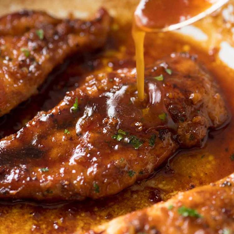 Close up of Honey Garlic Sauce being drizzled over Honey Garlic Chicken