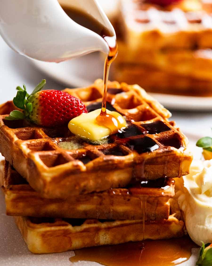 Pouring syrup over stack of Waffles