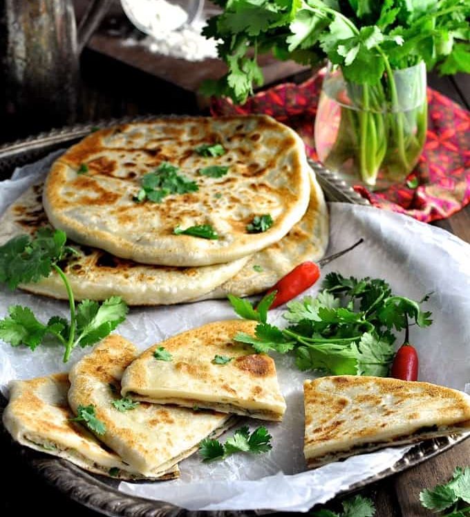 Aloo Paratha (Indian Potato Stuffed Flatbreads) filled with mashed potato and spiced beef on a tray, ready to be served.