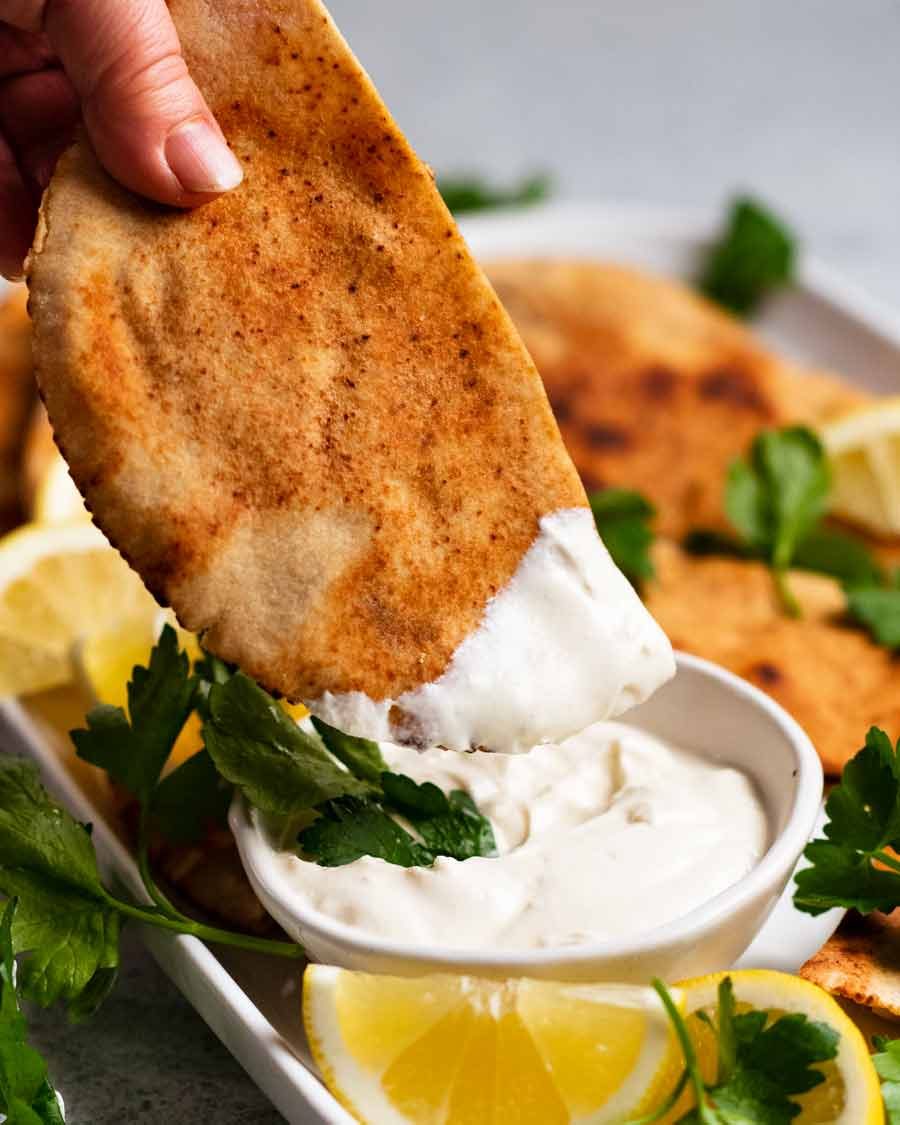 Dipping Arayes into Tahini yogurt sauce (Lebanese Meat Stuffed Crispy Pita)