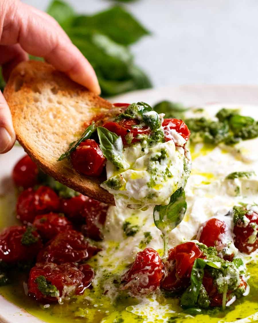 Scooping up Burst tomato burrata salad with crusty bread