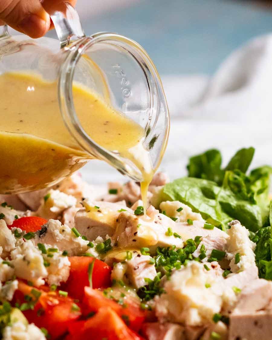 Pouring dressing over Cobb Salad