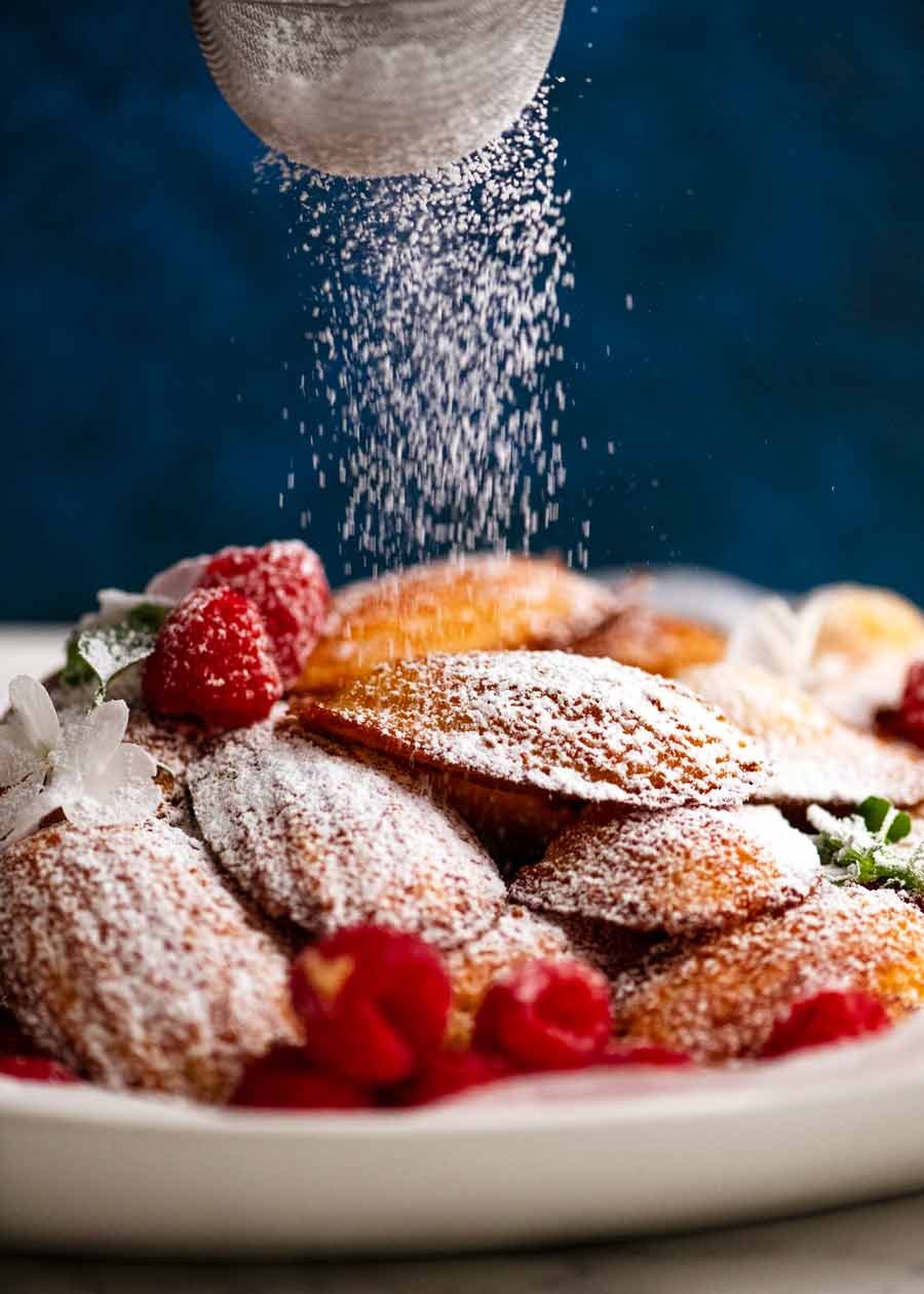 Dusting Madeleines with icing sugar