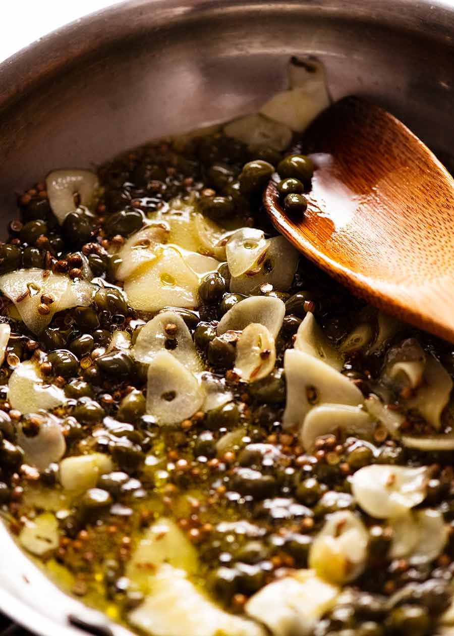 Close up of garlic cumin coriander caper dressing for Yotam Ottolenghi's Green Bean Salad