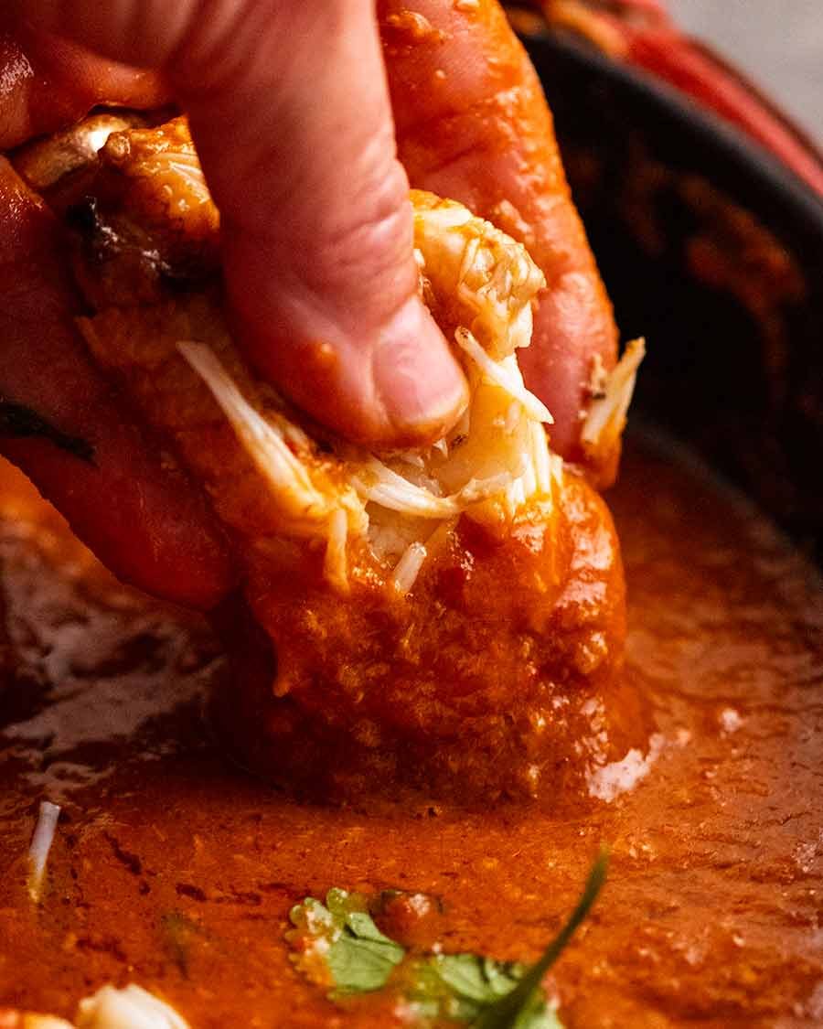 Dipping mud crab claw into Singapore Chilli Crab sauce