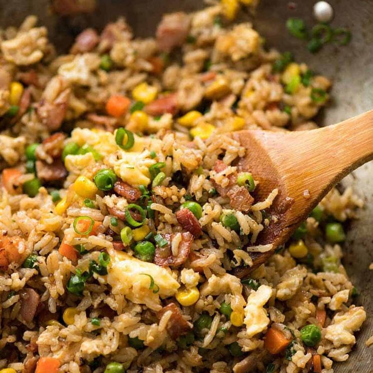 Close up of Egg Fried Rice in a wok with a wooden spoon, fresh off the stove