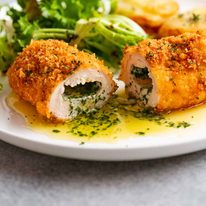 Cut open piece of Chicken Kiev on a plate, ready to be eaten