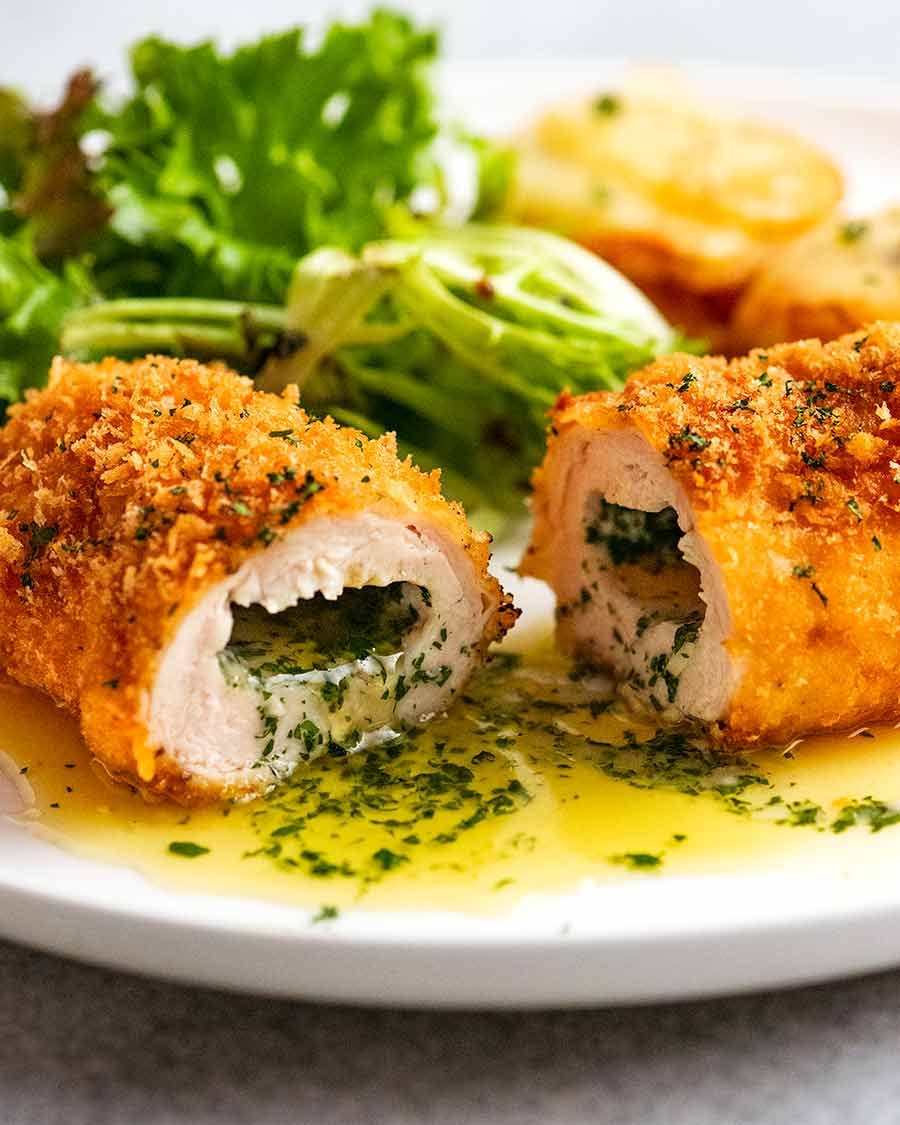 Cut open piece of Chicken Kiev on a plate, ready to be eaten