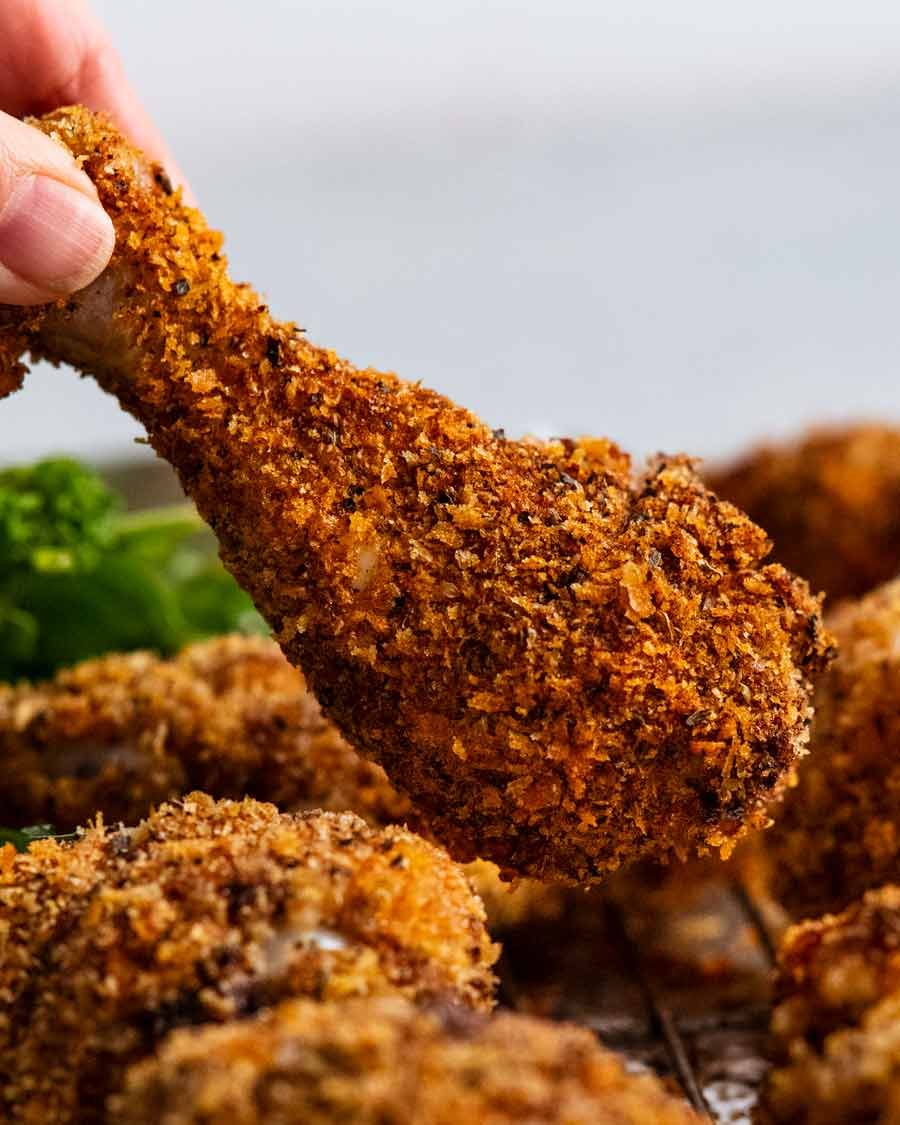 Holding Crunchy crumbed chicken drumsticks