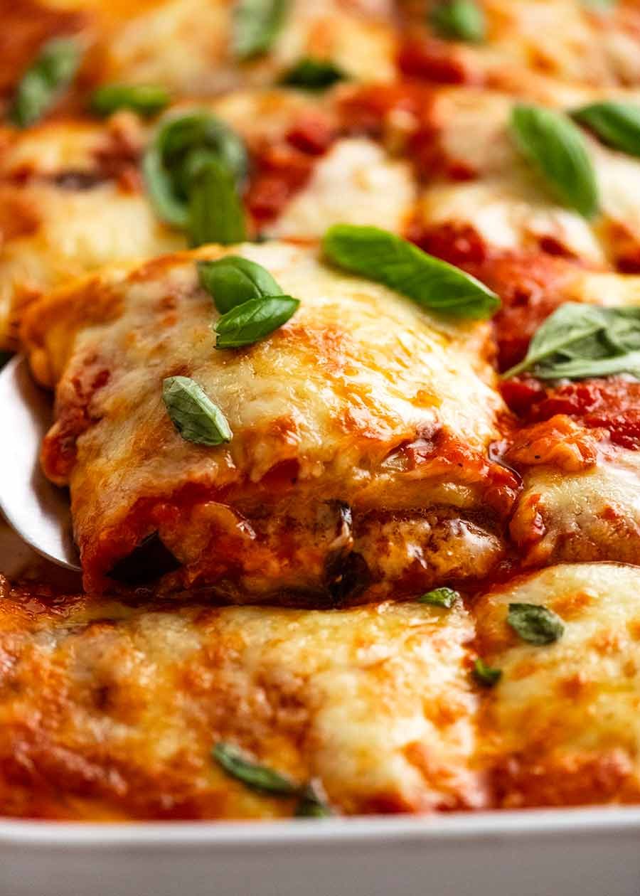 Close up of a piece of Eggplant Parmigiana being scooped out of a dish