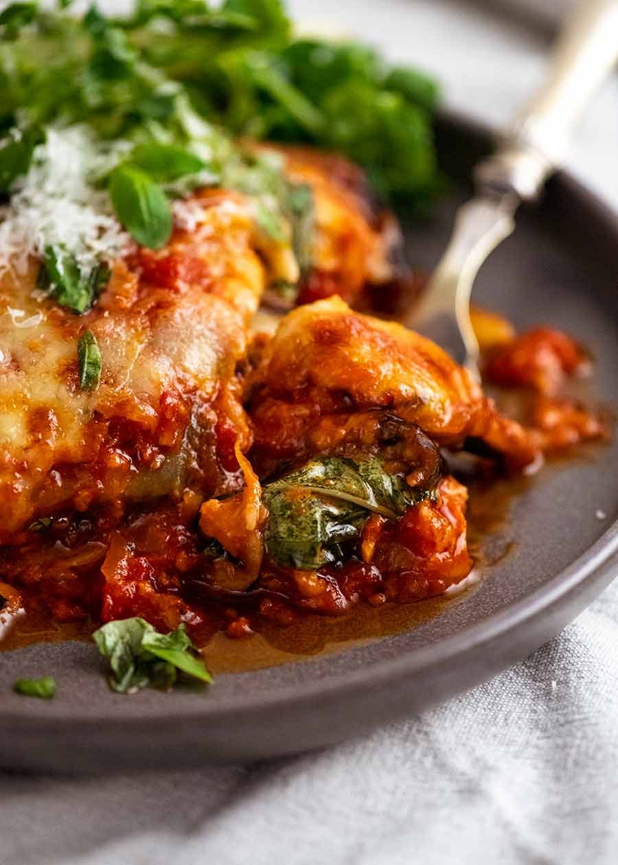 Close up of fork eating Eggplant Parmigiana