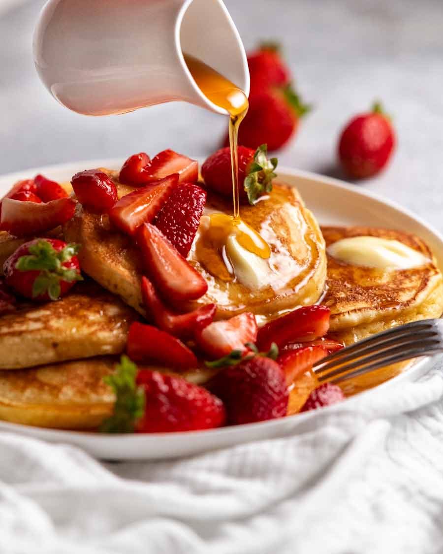 Pouring maple syrup over Ricotta pancakes