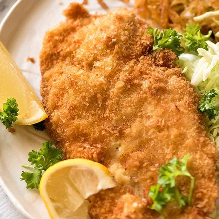 Overhead photo of crispy Schnitzel with lemon wedges