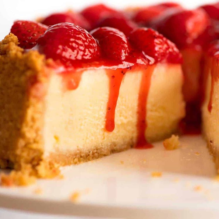 Close up of slice of Strawberry Cheesecake with Strawberry Sauce dripping down the side