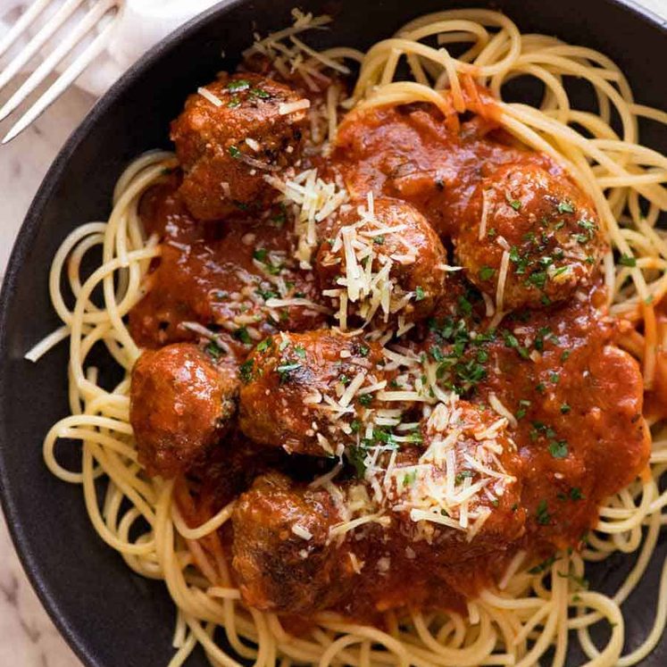 Overhead photo of Italian Meatballs in a rustic black bowl garnished with parmesan, ready to be eaten