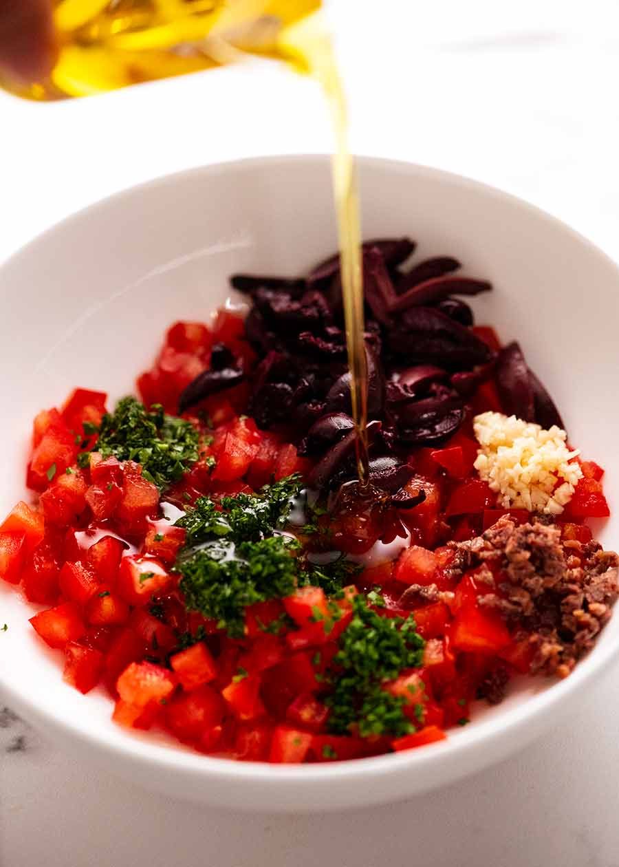 Pouring olive oil over Sauce Vierge in a bowl