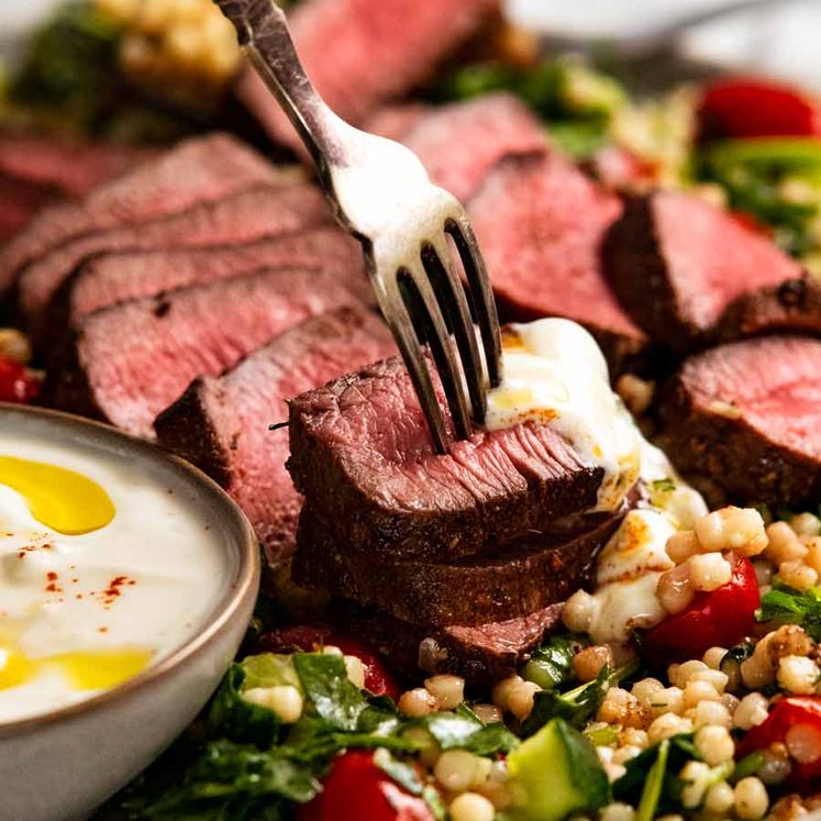 Fork picking up a slice of Moroccan lamb backstrap with yogurt sauce