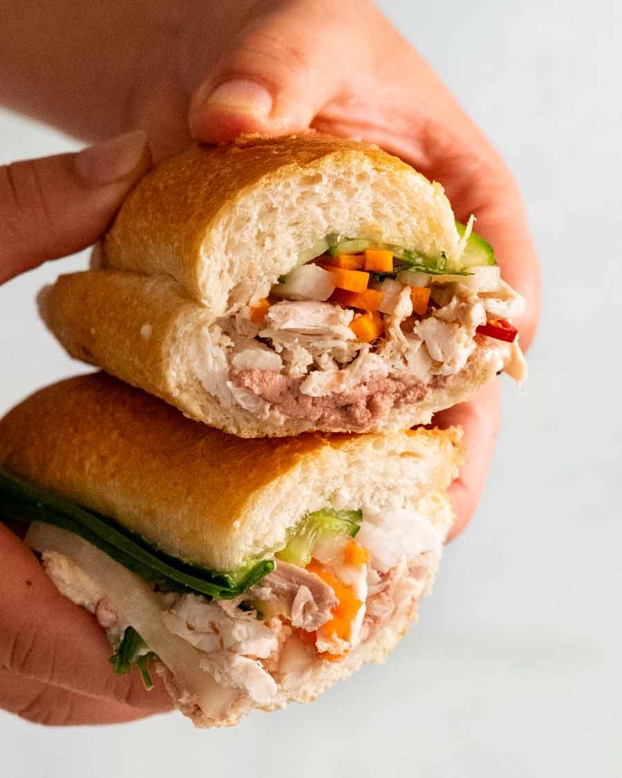 Hand holding cut open Chicken banh mi