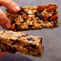 Close up photo of hand holding homemade Muesli bars (granola bars)