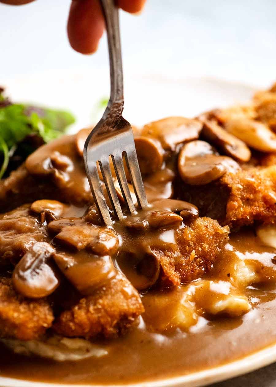 Fork picking up a piece of schnitzel smothered in Mushroom Gravy