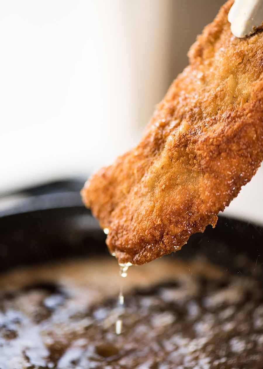 Freshly cooked schnitzel being pulled out of hot foil