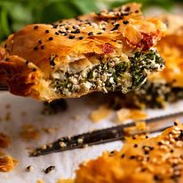 Close up lifting up a slice of Spanakopita