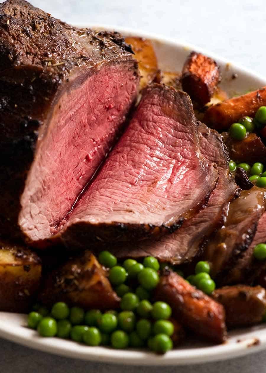marinated-roast-beef_7-1 Sliced Marinated Roast Beef on a platter with roasted vegetables, ready to be served