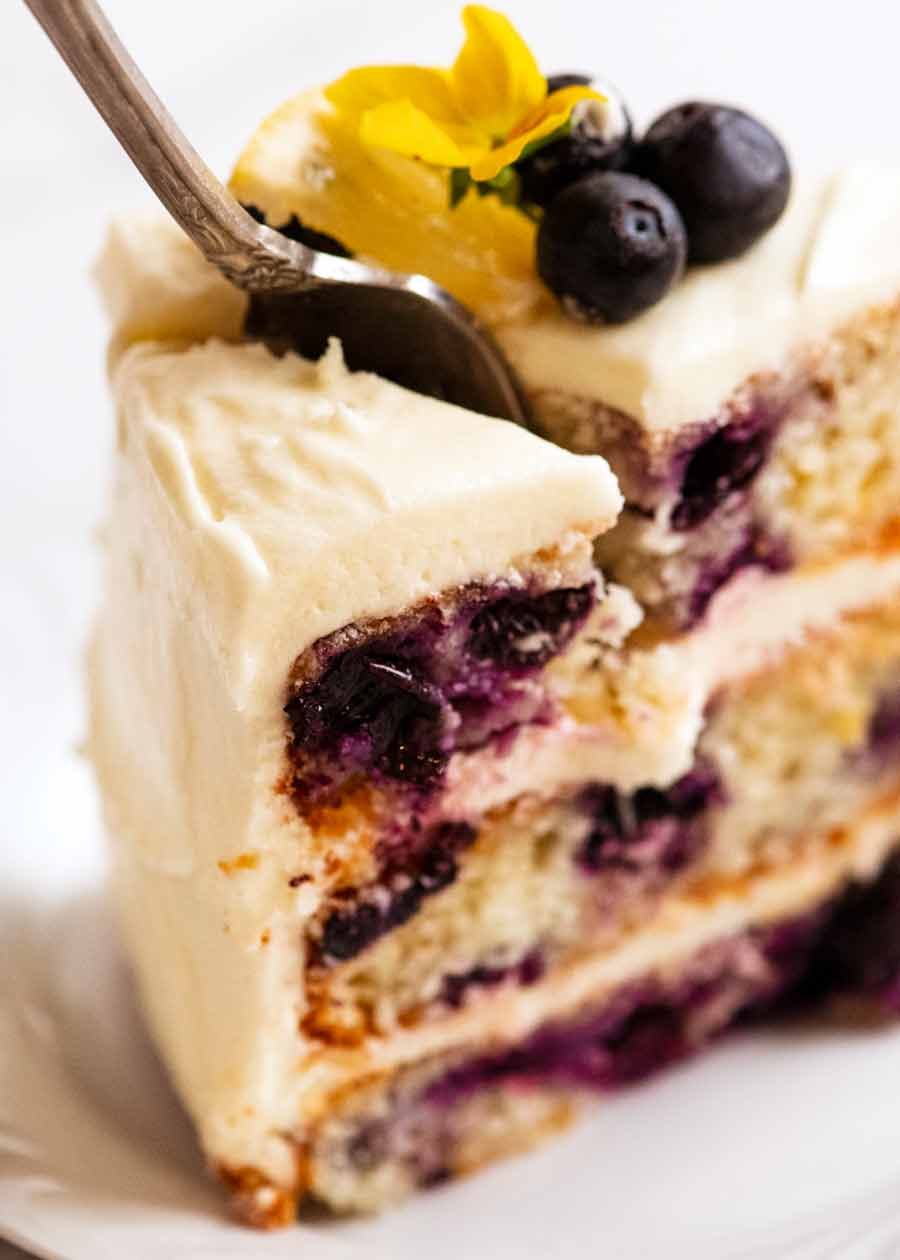 blueberry-cake-with-lemon-cream-cheese-frosting_5 Fork cutting into Blueberry Cake with Lemon Cream Cheese Frosting