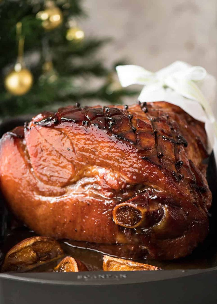 maple-glazed-ham-7 A baked ham glistening with a maple brown sugar glaze on a large white platter.