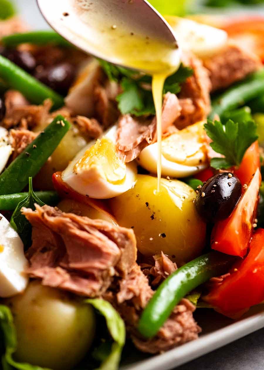 salade-nicoise-v2_4 Drizzling lemon dressing over Salad Nicoise - French Tuna Salad