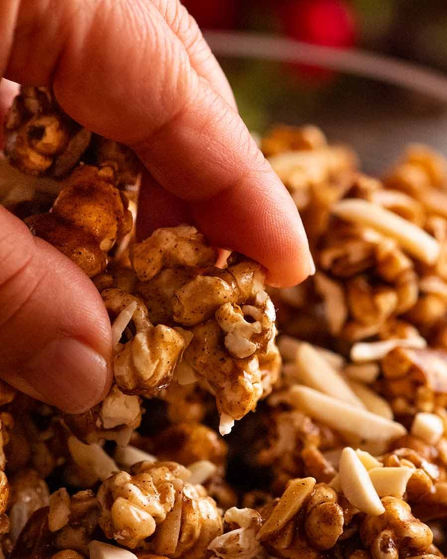 holiday-caramel-popcorn_5 Close up of hand picking up Christmas Popcorn Candy